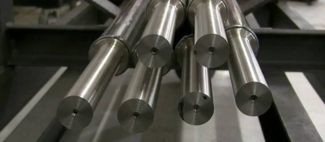 Close-up of cylindrical metal rods positioned for a friction welding process, showcasing the precise alignment and smooth, reflective surfaces of the rods.