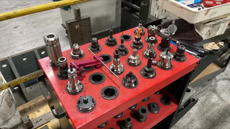 A collection of precision tooling components used for friction welding processes, organized on a red workstation in an industrial setting.