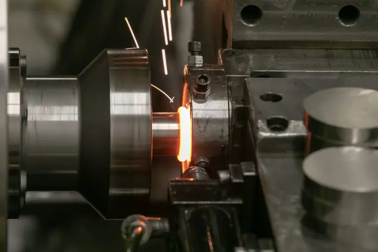 Close-up view of the inertia friction welding process with sparks flying as metal components are welded together.