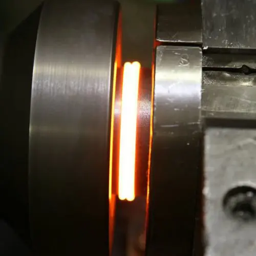 Close-up view of the inertia friction welding process with metal components heated and bonded together.